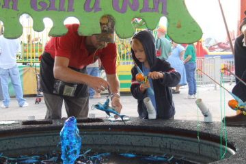 This young boy intently fishing for a prize from a pond of blue water at the Anderson County Fair, SC