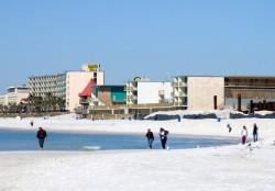 A family walks down the white sandy beach of Panama City Beach, FL.