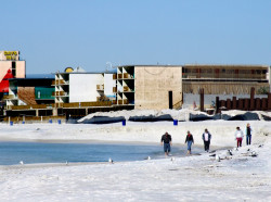 A family walks down the white sandy beach of Panama City Beach, FL.